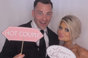 bride and groom in wedding photo booth with props