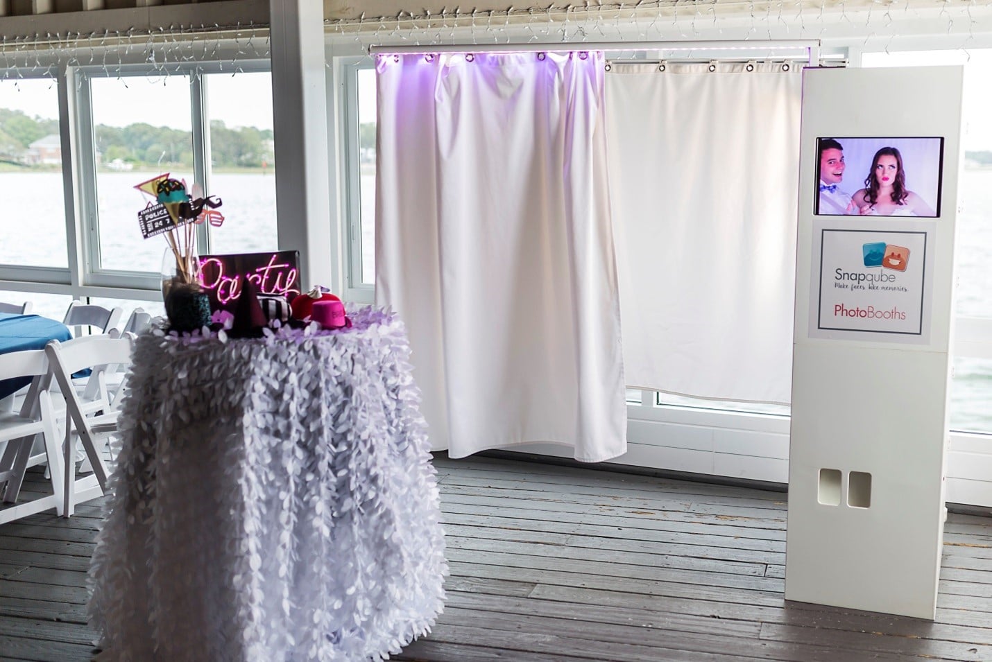 all white enclosed photo booth rental setup at wedding reception with prop table