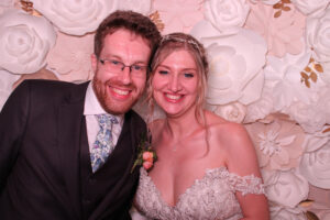 Photo of couple in wedding photo booth in Virginia Beach with white flower backdrop