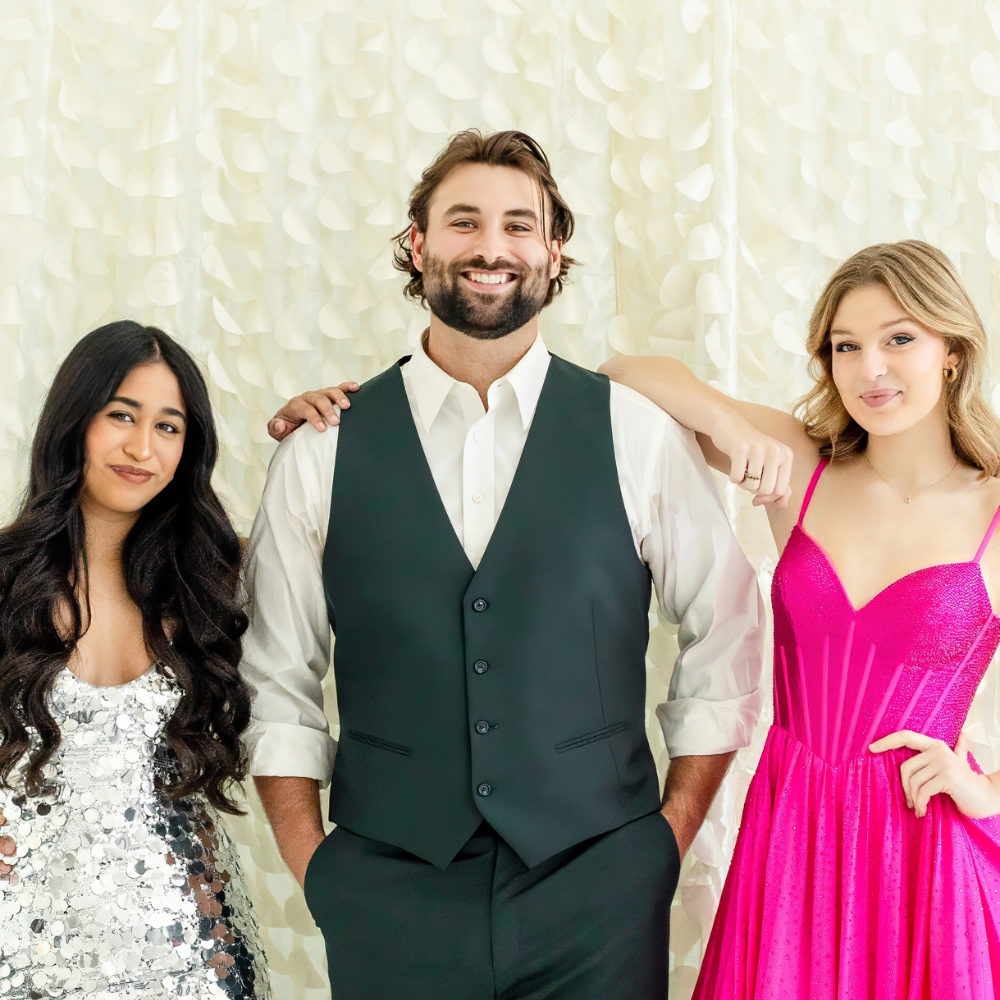 two girls and a guy posing in photo booth in front of an ivory mermaid pattern backdrop