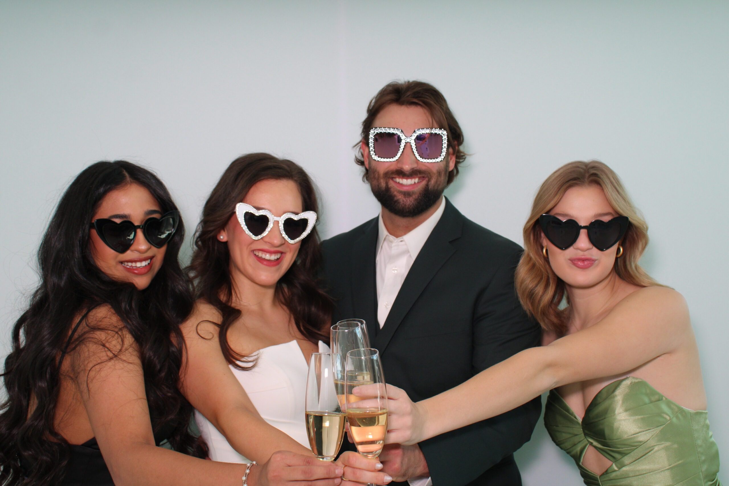 bride and groom with two bridesmaids toasting champagne in open air wedding photo booth