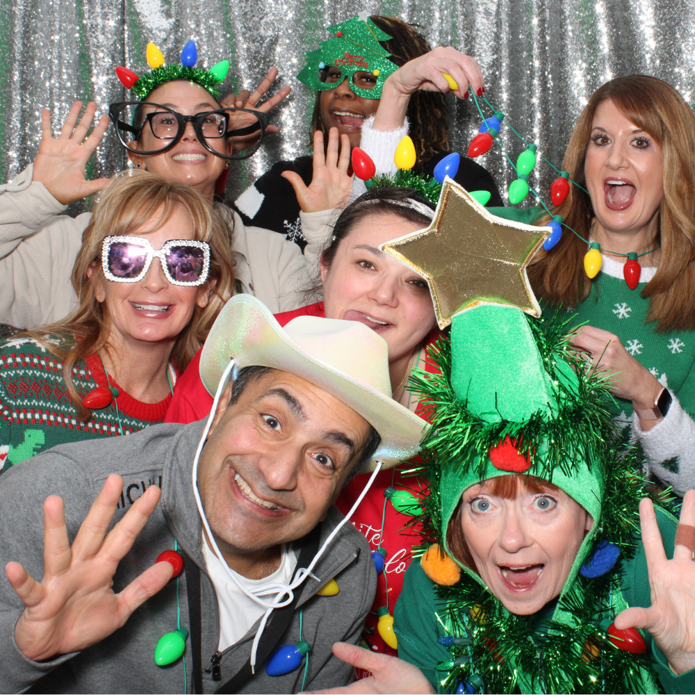 group of employees posing in photo booth for company holiday party